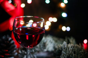 glass of red wine with holiday decorations in the background
