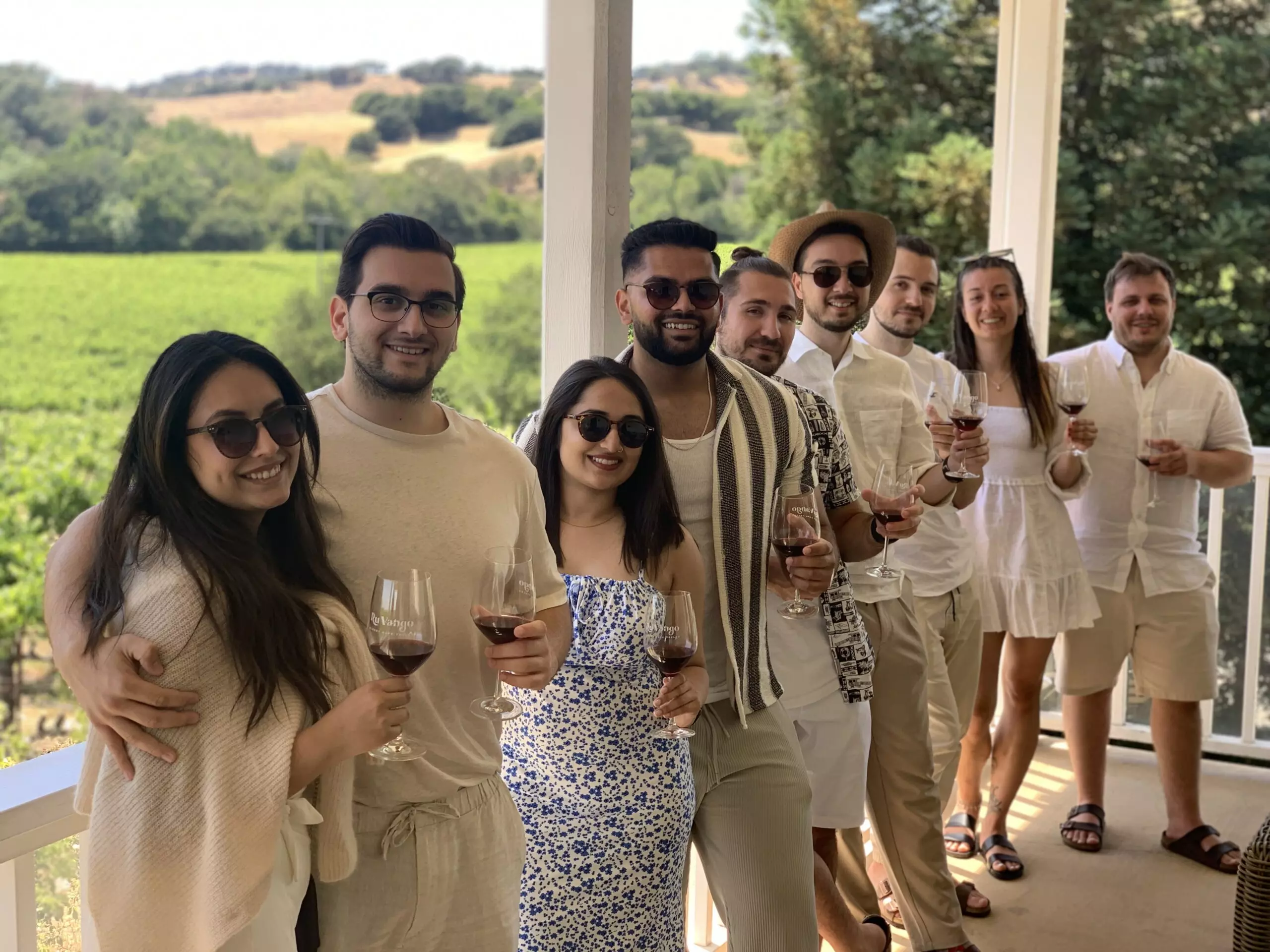 Large group of friends enjoying a sunny day wine tasting experience at vineyard rows in Napa Valley